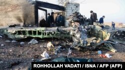 People stand near the wreckage after a Ukrainian plane carrying 176 passengers was shot down by the Revolutionary Guard near Imam Khomeini Airport in Tehran on January 8, 2020. 