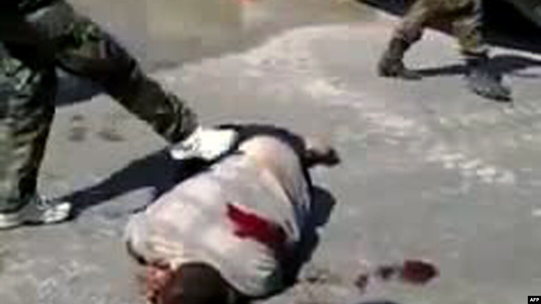 A YouTube video grab from September showed what antiregime activists said are pro-government militia members dressed as soldiers kicking the corpse of a man in the city of Homs, Syria.