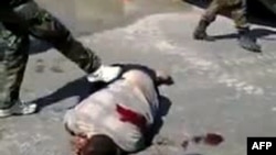 A YouTube video grab from September showed what antiregime activists said are pro-government militia members dressed as soldiers kicking the corpse of a man in the city of Homs, Syria.