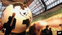 Kopenhagendə nəhəng Yer kürəsinin qarşısında biri mobil telefonla danışır.