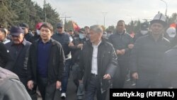 Митингчилердин алдында мурдагы президент Атамбаев, мурдагы премьер-министрлер Сапар Исаков жана Өмүрбек Бабанов баратышат. 9-октябрь 2020-жыл. 
