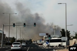 Motorists drive past a plume of smoke rising from a reported Iranian strike in the industrial district of Doha, Qatar, on March 1.