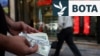 Një tregtar valutash mban kartëmonedha 100 dollarëshe në një kohë kur vlera e rialit iranian ka rënë, Teheran, Iran, 2 maj.