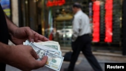 A currency dealer holds $100 bills, as the value of the Iranian rial drops, in Tehran, Iran on May 2.