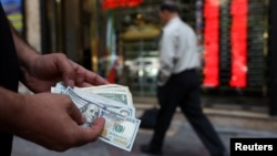 یک صراف در تهران، پایتخت ایران، با کاهش ارزش ریال، بانکنوت‌های ۱۰۰ دالری را در دست دارد،تاریخ ۲ می ۲۰۲۶