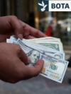Një tregtar valutash mban kartëmonedha 100 dollarëshe në një kohë kur vlera e rialit iranian ka rënë, Teheran, Iran, 2 maj.