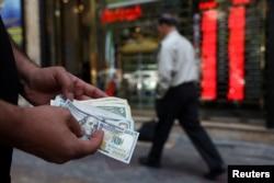 A currency dealer holds $100 bills, as the value of the Iranian rial drops, in Tehran, Iran on May 2.