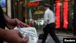 A currency dealer holds one-hundred-dollar bills in Tehran. (file photo)
