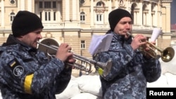 Militari ucraineni cântă la trompetă în fața Operei de la Odesa, Ucraina, 8 martie 2022.