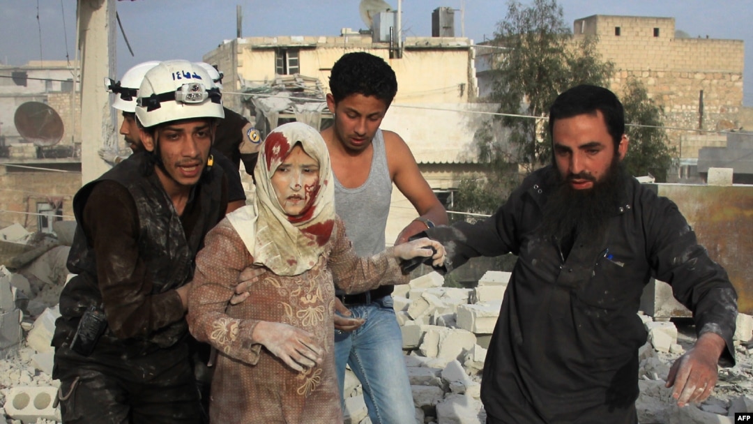 Syrian rescue workers and residents help an injured woman following a reported air strike by government forces on the rebel-held neighborhood of Haydariya in the northern city of Aleppo on April 10.