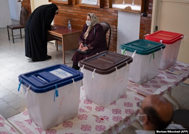 A woman fills out her registration form before voting at a polling station in Tehran on June 18.