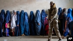 A Taliban fighter stands guard as women wait to receive food rations distributed by a humanitarian aid group in Kabul, Afghanistan, in May 2023. (file photo)