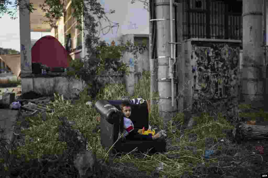 A young boy sits in an old armchair outside the old international airport in Athens, which is being used as a temporary camp for refugees. (AFP/Angelos Tzortzinis)