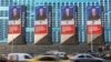 Cars drive past electronic screens on the facade of a building showing an image of Russian President Vladimir Putin in Moscow on February 29.