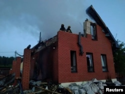 Пожежники працюють біля пошкодженого будинку після атаки українських дронів у Московській області Росії, 17 травня 2026 року