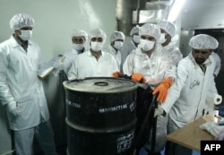 Iranian technicians remove a container of radioactive uranium, or yellow cake, sealed by the International Atomic Energy Agency, at the Isfahan Uranium Conversion Facilities in 2005.