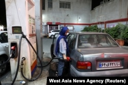 An Iranian woman fills her car with fuel at a gas station after the missile attack on Israel, in Tehran on October 1.