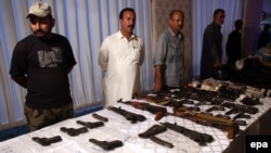 Pakistani security official displays weapons recovered during a security operation in Karachi on November 7.