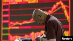 An investor takes notes in front of an electronic board showing stock information at a brokerage office in Beijing on July 7 as China's stock market crashed.