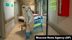 Medics wearing special suits to protect against the coronavirus transfer a patient with the illness to a COVID ward in a Moscow hospital. 