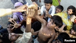 Pakistanis reach for food distributed from a truck in a village in Muzaffargarh district of Punjab Province.