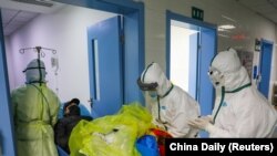 Medicinski radnici u zaštitnim odijelima premještaju novog pacijenta s koronavirusom u izolirano odjeljenje bolnice u Wuhanu, provincija Hubei, Kina, 6. februar 2020.