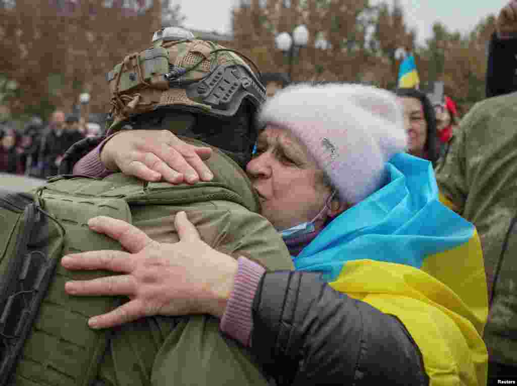 Възрастна жена прегръща украински войник на фона на украински знамена в центъра на Херсон, 12 ноември 2022 г.