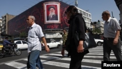 People walk past a billboard with an image of Iran's late Supreme Leader Ayatollah Ali Khamenei in Tehran on July 13. 