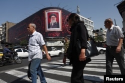 People walk past a billboard with an image of Iran's late Supreme Leader Ayatollah Ali Khamenei in Tehran on July 13.