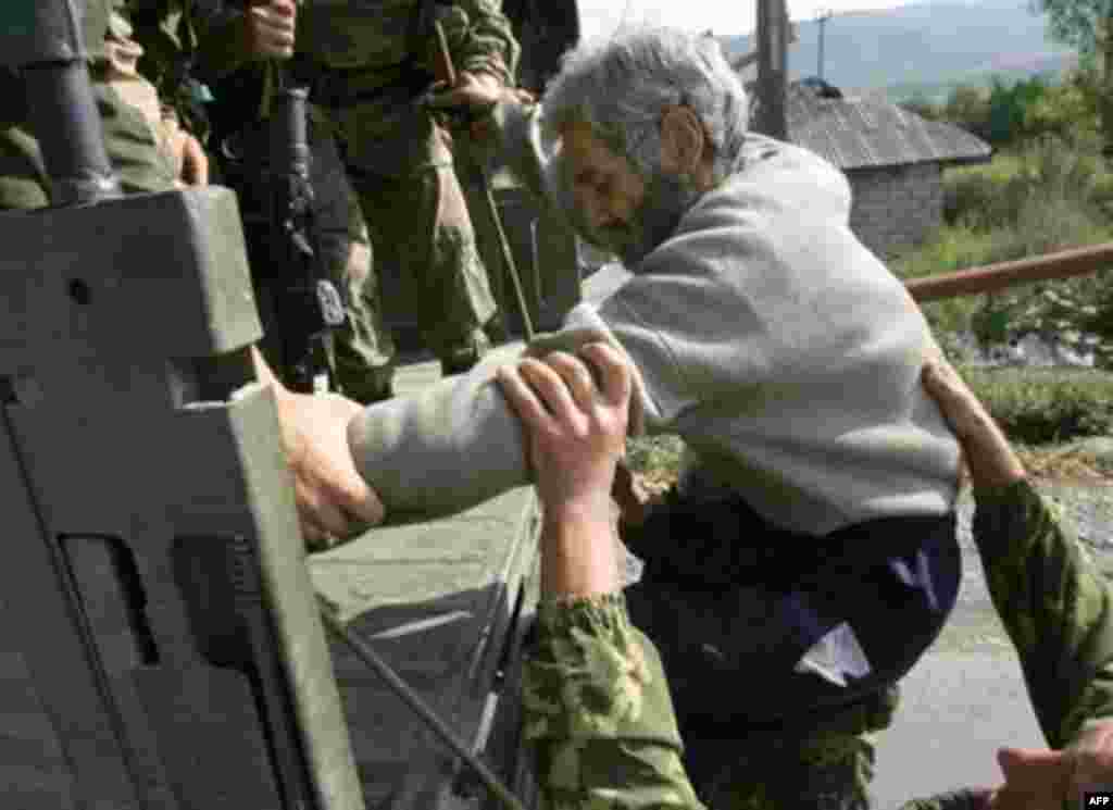 Российские военнослужащие помогают Тариелу Басишвили сесть в кузов грузовика в селе Курта, 5 сентября 2008 года