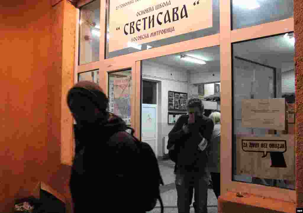 Членови на изборната комисија го напуштаат гласачкото место во училиштето „Свети Сава“ во Митровица откако беше нападнато од непознати лица. 