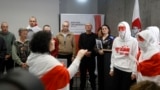 Exiled Belarusian opposition leader Svetlana Tikhanovskaya (3rdR) looks on as she stands next to members of the Belarusian Volny Chor (R) performing during a press conference with freed political prisoners, among them Belsat journalist Iryna Slaunikava (2
