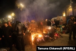 Protestors alongside a burning barricade.