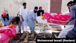 Afghan Sikh men carry coffins before light the funeral pyre for the victims who were killed during attack at Sikh religious complex on March 25.