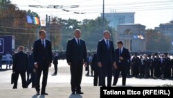 Liderul informal al socialiştilor Igor Dodon (centru) şi democraţii Andrian Candu (stânga) şi Pavel Filip depun flori de Ziua Independenței, pe fundalul scandărilor de după cordoanele de poliţie ale opoziţiei pro-europene