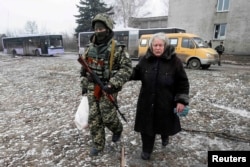 Гуманитарлық жәрдем заттарын алған егде әйелге көмектесіп келе жатқан украиналық әскери қызметкер. Дебальцево, 6 ақпан 2015 жыл.