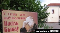 Шыльда паміж домам на вуліцы Вялікай Траецкай (у савецкі час — Алега Кашаваго) і старой камяніцай (яе адрас — вул. Савецкая, 8), дзе напачатку была рэдакцыя абласной газэты, у якой працаваў пісьменьнік Васіль Быкаў
