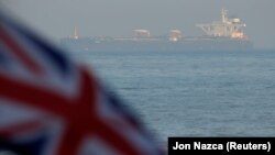 The British Union Jack flag flies in front of Iranian oil tanker Grace 1 as it sits anchored after it was seized in July by British Royal Marines off the coast of the British Mediterranean territory on suspicion of violating sanctions against Syria, in th