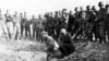 In this photo from 1941, Soviet prisoners dig their own graves as German soldiers look on impassively.