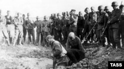 In this photo from 1941, Soviet prisoners dig their own graves as German soldiers look on impassively.