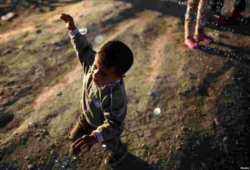 A child plays with soap bubbles at a makeshift camp for migrants and refugees at the Greek-Macedonian border near the village of Idomeni, Greece. (Reuters/Stoyan Nenov)