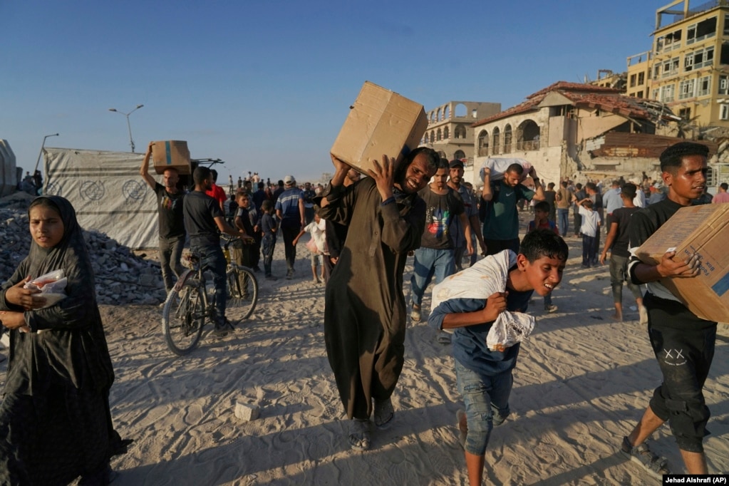 Palestinezë të të gjitha moshave duke bartur pako e thasë me ndihma.