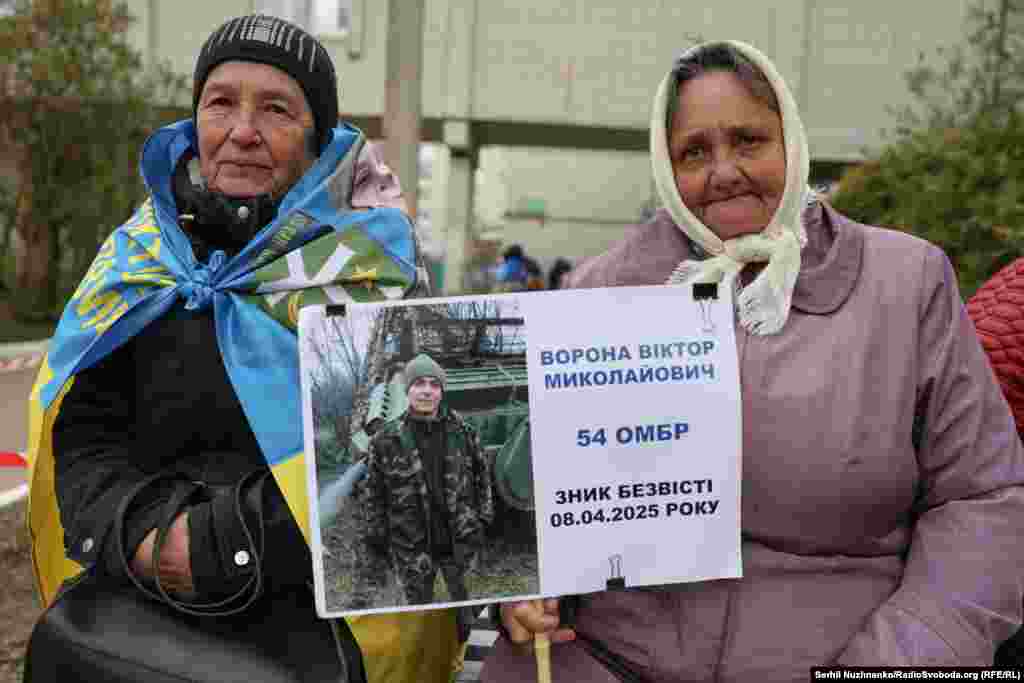 На лавці сидять дві жінки, рідні сестри Любов і Тамара. Любов тримає фото сина Віктора, йому 52 роки. Працював на виробництві меблів. Пішов на війну в 2022 році добровольцем. Рік тому зник безвісти.«Він працював у Гостомелі, коли розпочалась війна, пережив окупацію, після деокупації приїхав додому на Чернігівщину до мене, і звідси відразу пішов до війська. Я сподіваюся, я ні хвилиночки не сумніваюся, що він повернеться. Я знаю. Рушничок йому посилаю в дорогу, кажу: «Синочок, я тобі рушничок посилаю, щоб ти по ньому повернувся додому», – розповідає мама військового.«Він ріс у мене на руках, це моє дитятко, ми його чекаємо вдома», – додає тітка Тамара