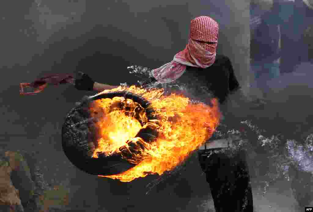 A Palestinian sets fire to a tire during clashes between hundreds of Palestinians and Israeli soldiers after a march marking the 65th Nakba day or Day of Catastrophe on May 15 in Betunia near the West Bank city of Ramallah. (AFP/Abbas Momani)