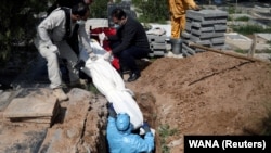 Men bury a victim of the coronavirus at Behesht Zahra cemetery in Tehran on March 24.