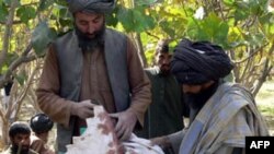 Villagers pose with a bloody piece of cloth in the village of Wocha Bakhta in Kandahar Province.