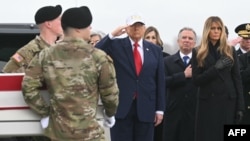 US President Donald Trump salutes as members of a US Army team carry the flagged-draped transfer case containing the remains of US soldier killed in the Middle East.