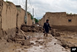 Një burrë ec pranë shtëpisë së vet të dëmtuar nga vërshimet në provincën Baghlan në veri të Afganistanit, 11 maj 2024.