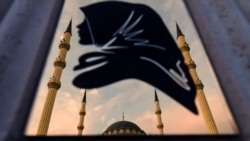 Chechnya -- A view of the Heart of Chechnya mosque is reflected on a metal panel with the silhouette of a woman wearing a scarf in central Grozny, July 24, 2017