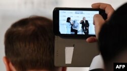 An onlooker films Iran's Foreign Minister Mohammad Javad Zarif (Right on the screen display) taking part in the panel discussion "A conversation with Iran" during the 56th Munich Security Conference (MSC) in Munich.